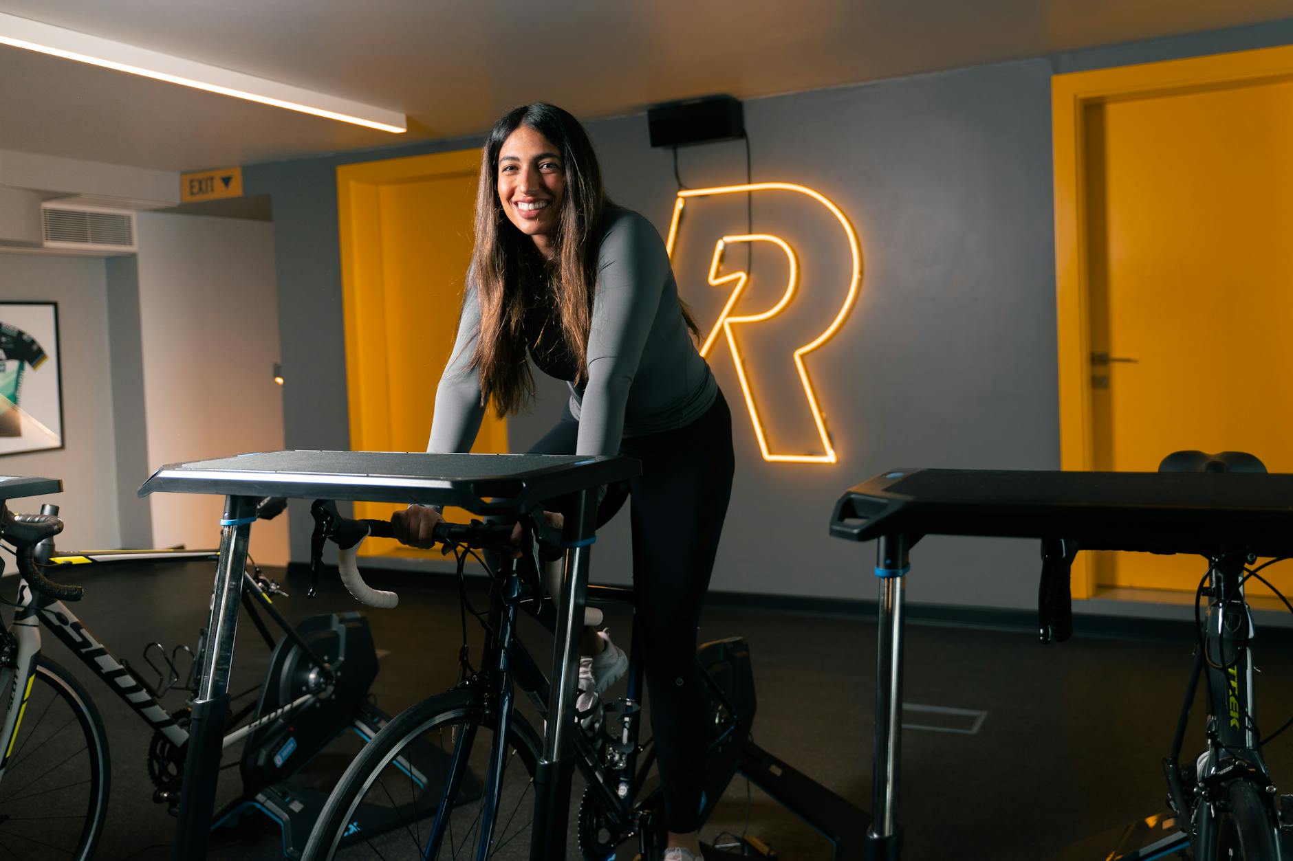 Smiling woman riding a stationary bike showing why indoor cycling is good for you