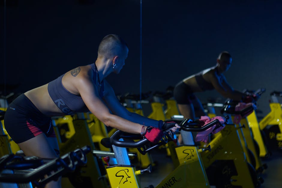 Woman riding a stationary spin bike at the gym, illustrating calorie burn during indoor cycling
