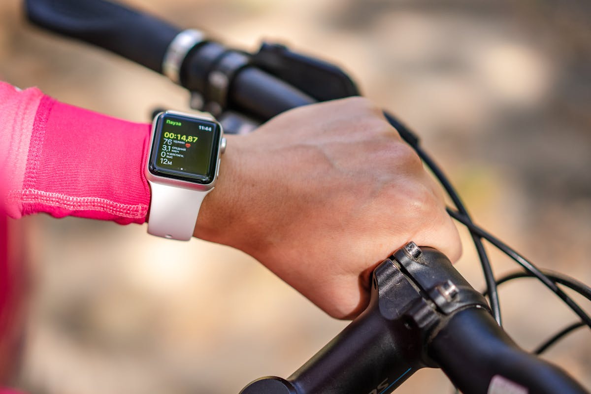 Cyclist checking smartwatch for fitness and training data while riding, illustrating AI training metrics