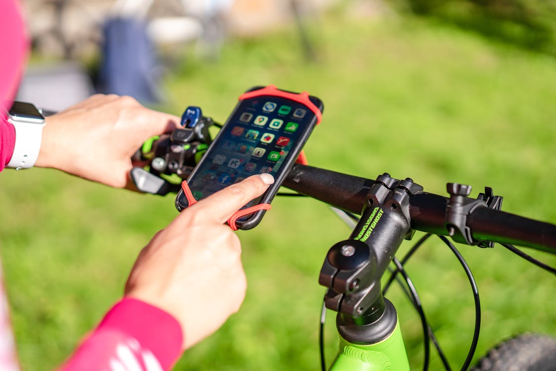 Cyclist using a smartphone app mounted on exercise bike handlebars for indoor training tracking