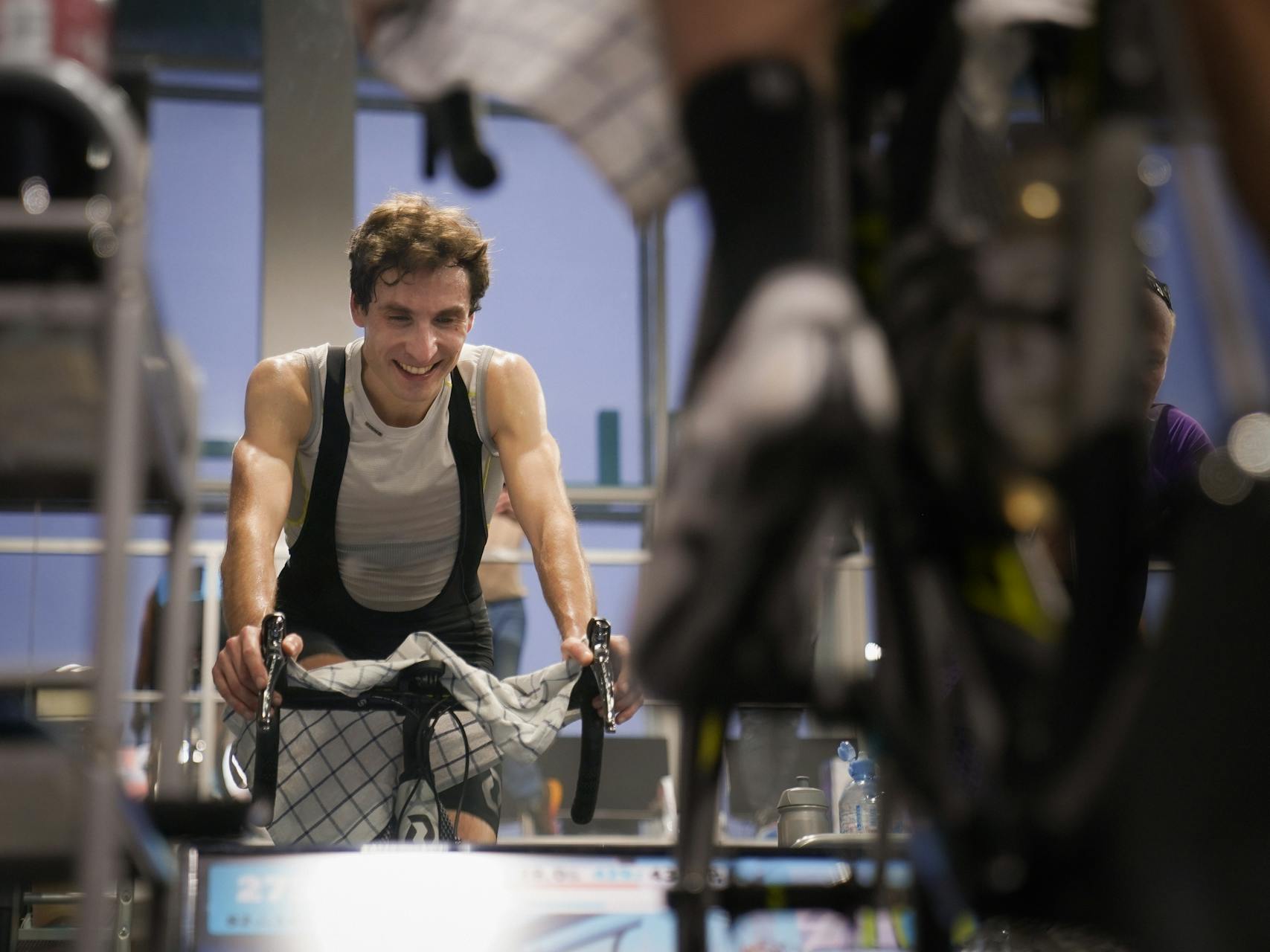 Man riding indoor exercise bike syncing workout data to phone after session